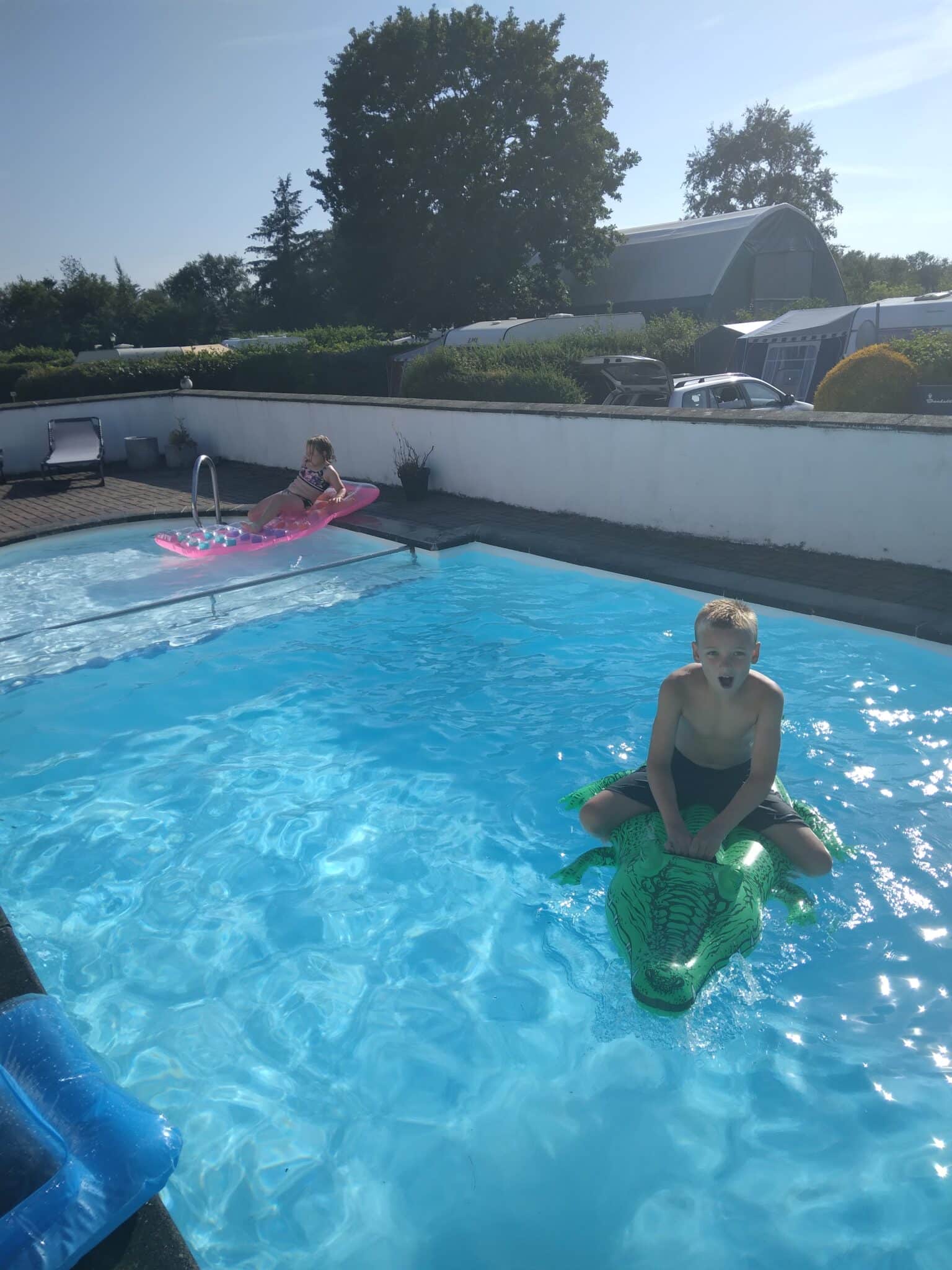 Børn leger i swimmingpool på en solrig dag