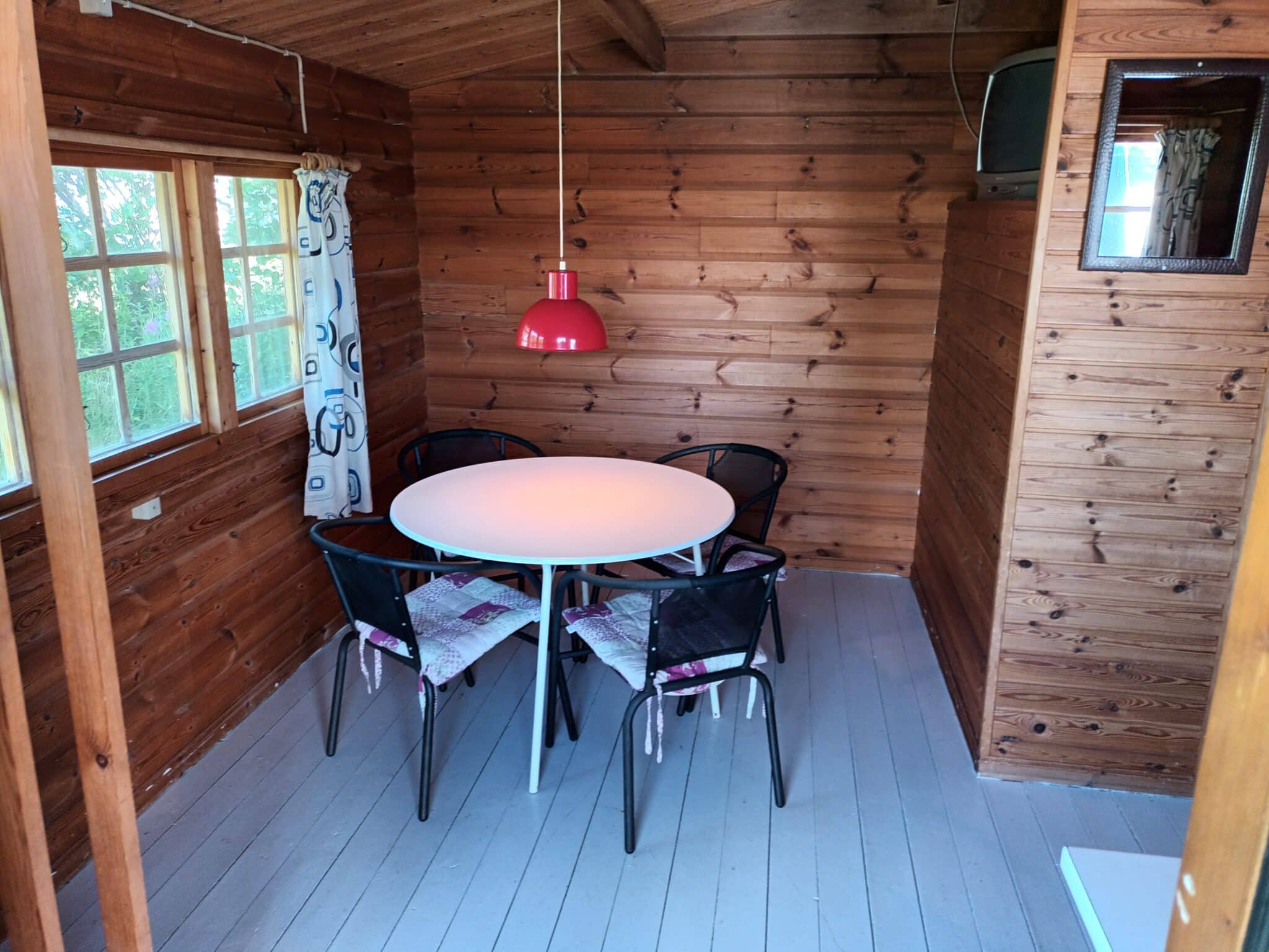 Lille træhytte med rundt bord og fire stole