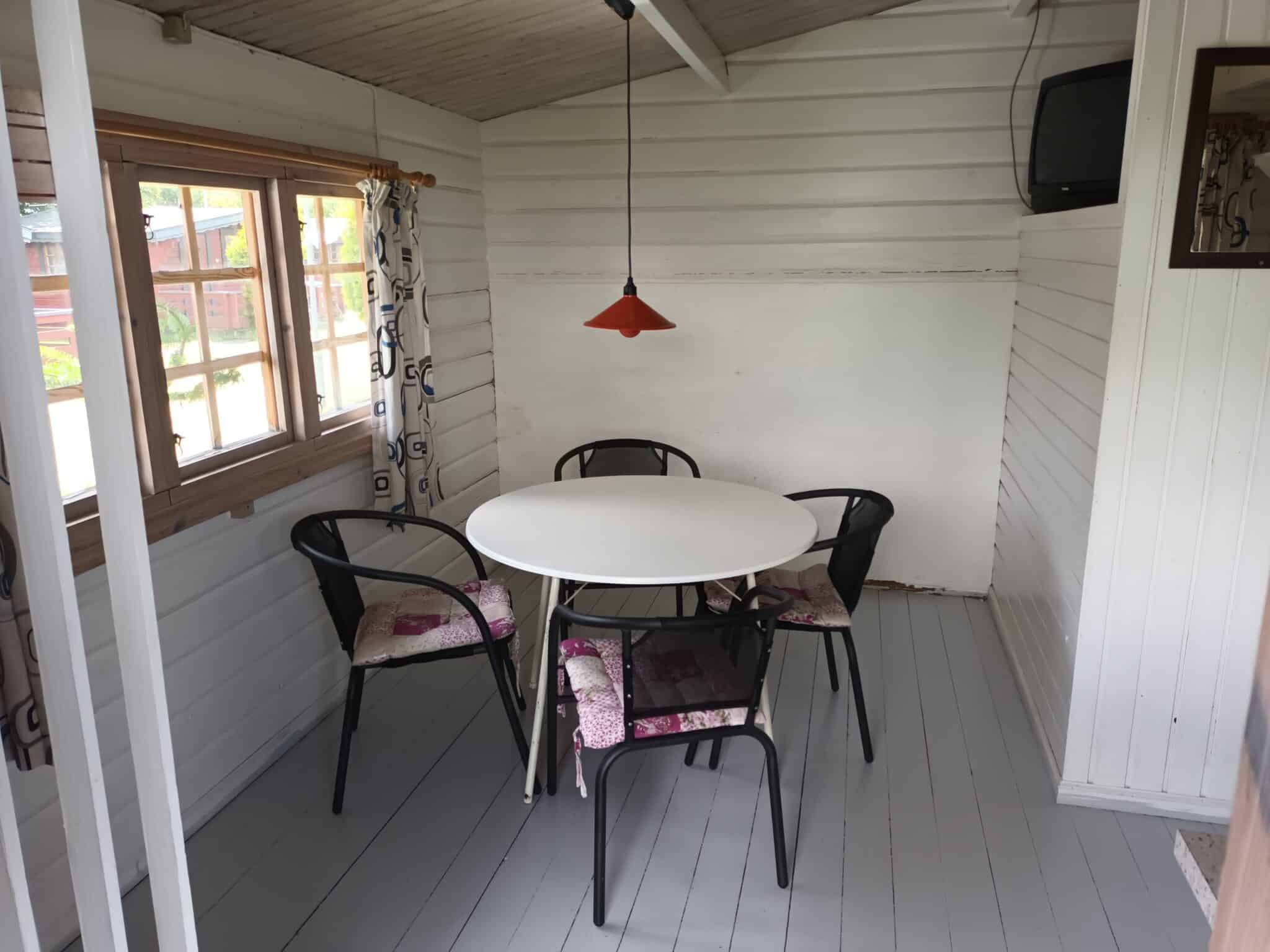 Lyst træinteriør med rundt bord og fire stole