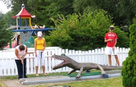 Folk spiller minigolf ved dinosaurbane udendørs