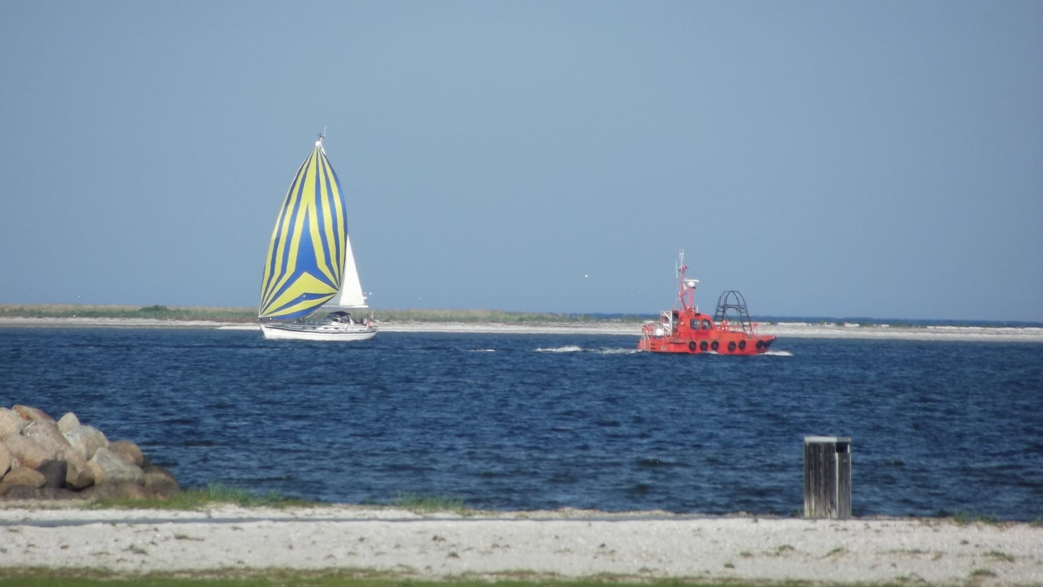 Sejlbåd og redningsbåd på havet ved kysten