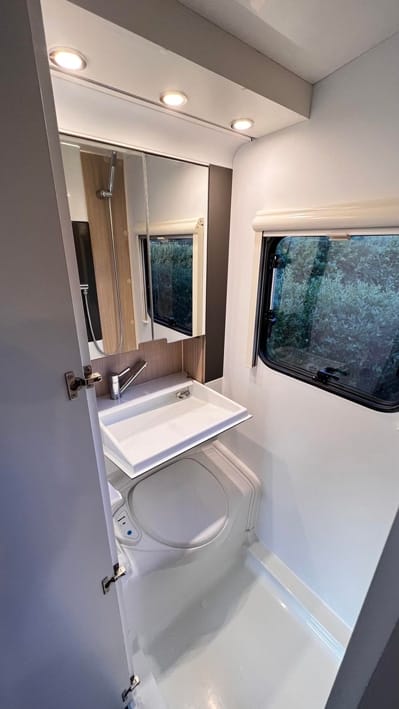Kompakt badeværelse i autocamper med vask og spejl.