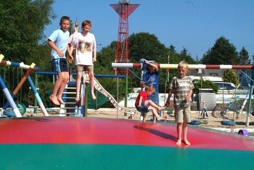 Børn leger på farverig hoppepude udendørs