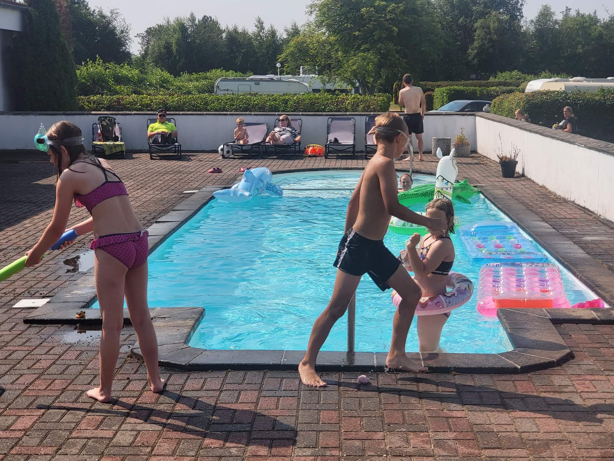 Børn leger ved swimmingpool på solrig dag