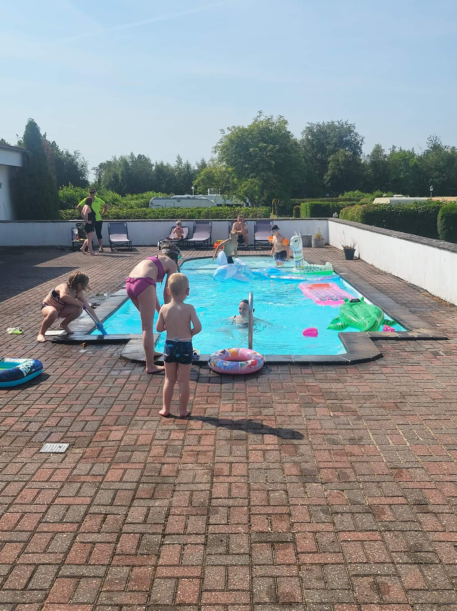 Børn leger i udendørs swimmingpool en solrig dag