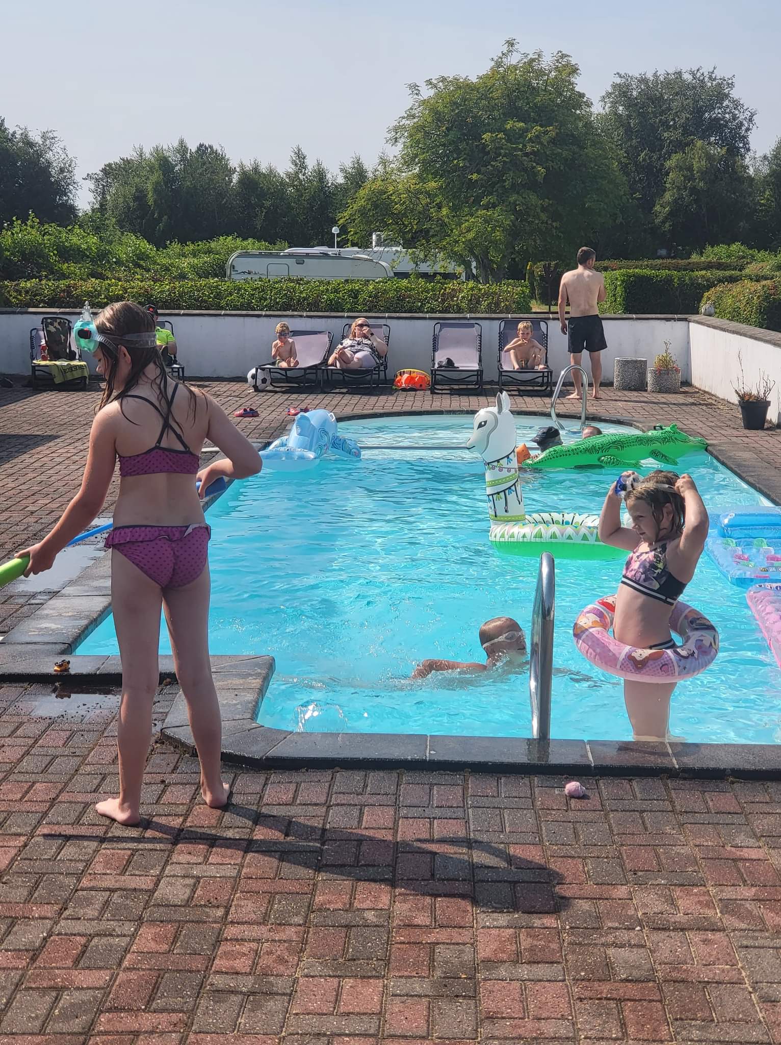 Børn leger i udendørs swimmingpool en solrig dag
