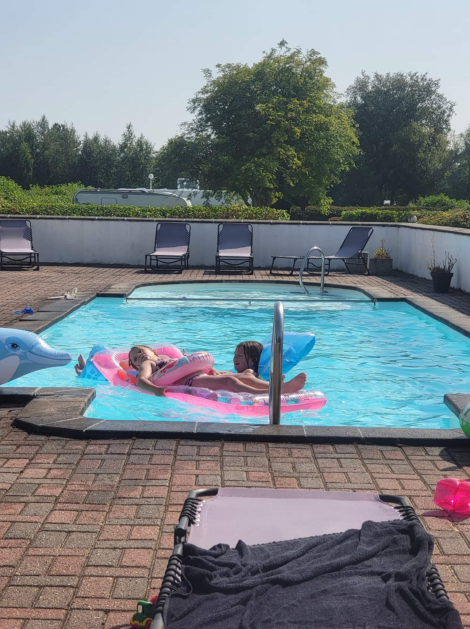 Børn leger på luftmadrasser i udendørs swimmingpool