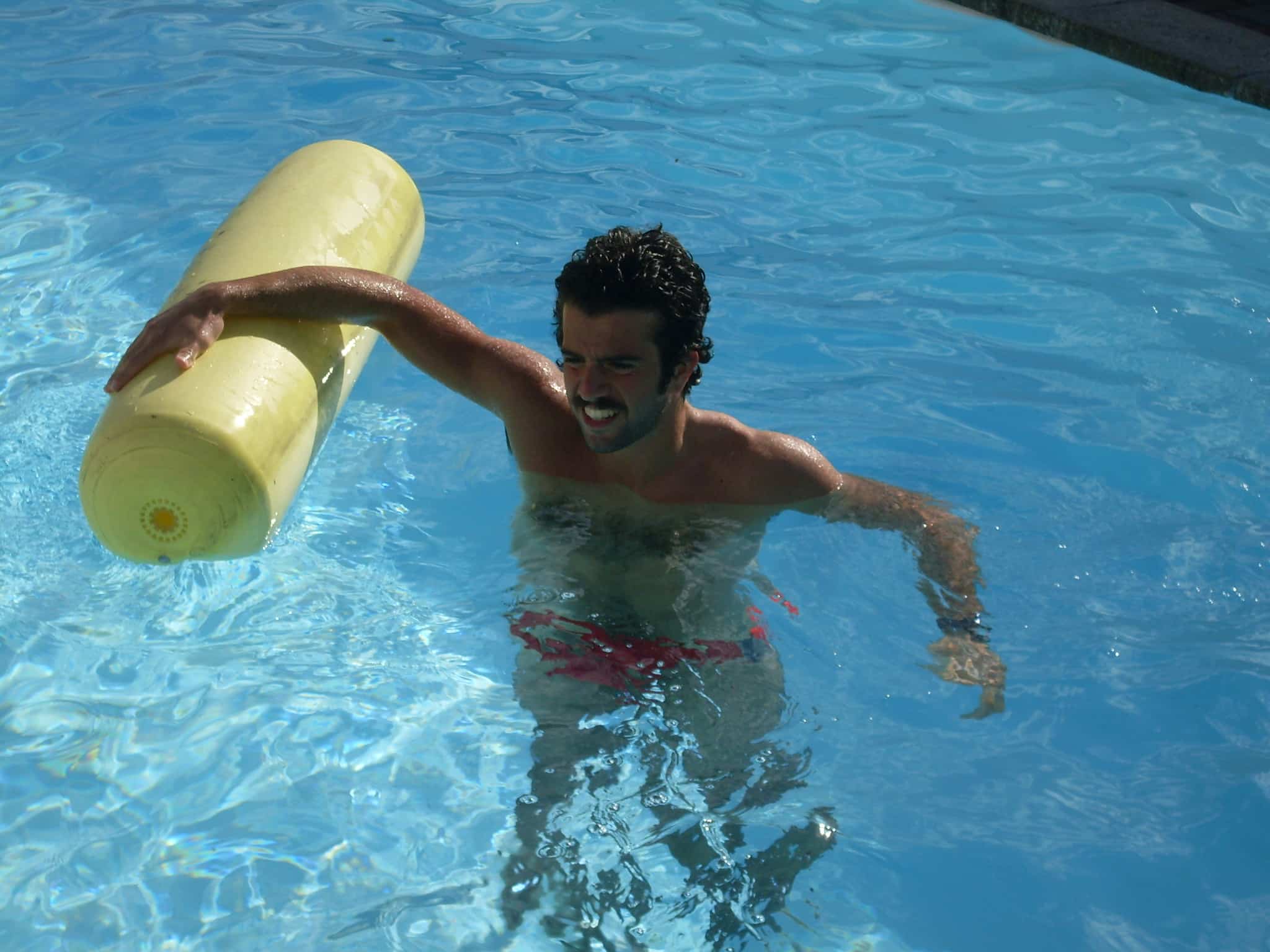 Mand svømmer i pool med oppustelig rulle